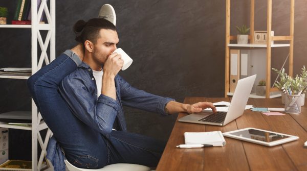 Flexibele man met koffie aan zijn pc.